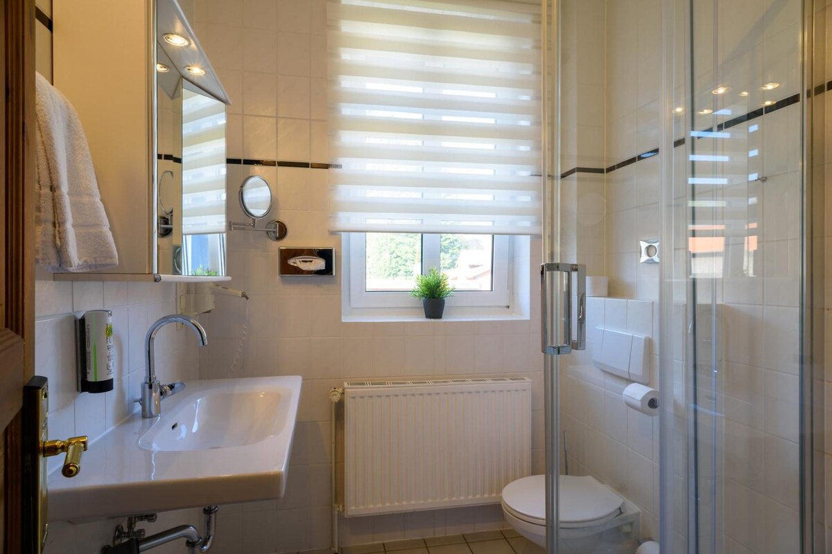 Ein modernes Badezimmer mit Waschbecken, Spiegel, Toilette und Dusche.