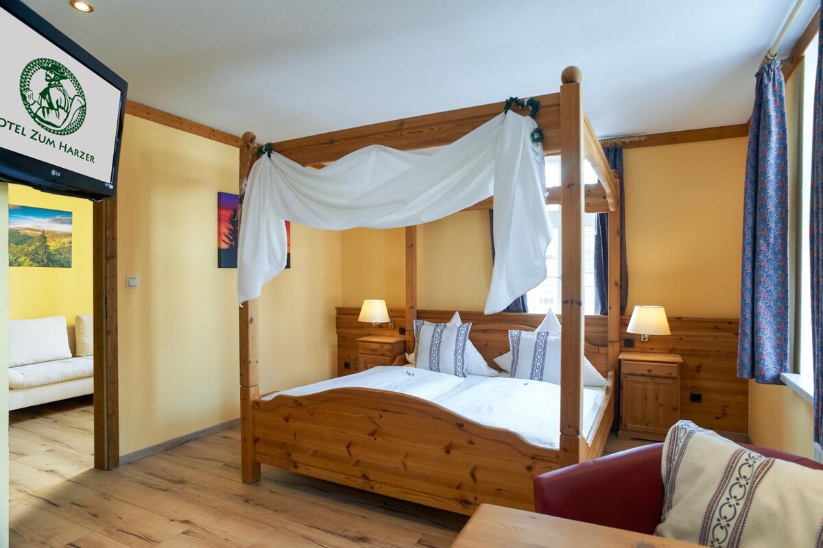 A four-poster bed with white bedding, wooden headboard, and nightstands with lamps.