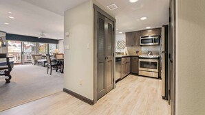 A modern kitchen with stainless steel appliances, a dining area with a table and chairs, and a view of the outside through large windows. - Saint James Place 111 (Beaver Creek)