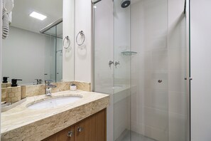 A modern bathroom with a marble sink, glass shower enclosure, and a large mirror. - La Vida Estilo Barroco (Sao Paulo)