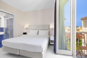 Ein Schlafzimmer mit Bett, Nachttischen, einem Fenster mit Vorhängen und Blick auf Gebäude.
