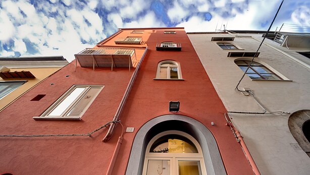 Un edificio con fachada roja, una entrada central en arco y varios ventanales.