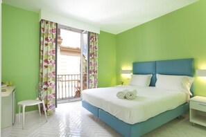 Ein Hotelzimmer mit Bett, Sessel, Nachttisch und einem Fenster mit Vorhängen.