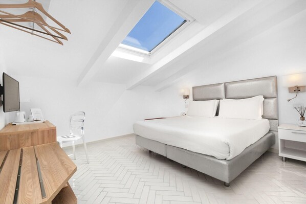 Un dormitorio moderno con tragaluces, una cama, una mesita de noche y un escritorio con una silla.