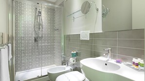 Ein modernes Badezimmer mit Dusche, zwei Waschbecken und einem großen Spiegel.