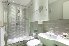 Ein modernes Badezimmer mit Dusche, zwei Waschbecken und einem großen Spiegel.