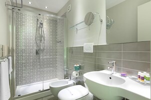 Un baño moderno con ducha, dos lavamanos y un espejo grande.