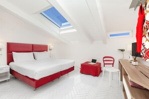 Une chambre à coucher moderne avec un lit rouge, des murs blancs et une lucarne.