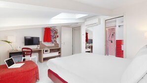 Ein modernes Hotelzimmer mit Bett, Schreibtisch, Fernseher und Duschbereich.