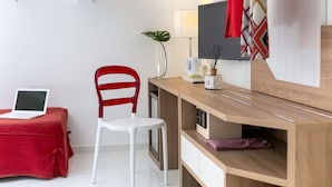 A modern room with a wooden desk, a red chair, a laptop, a lamp, and a TV. - Palazzo La Via - One Bedroom (Massa Lubrense)