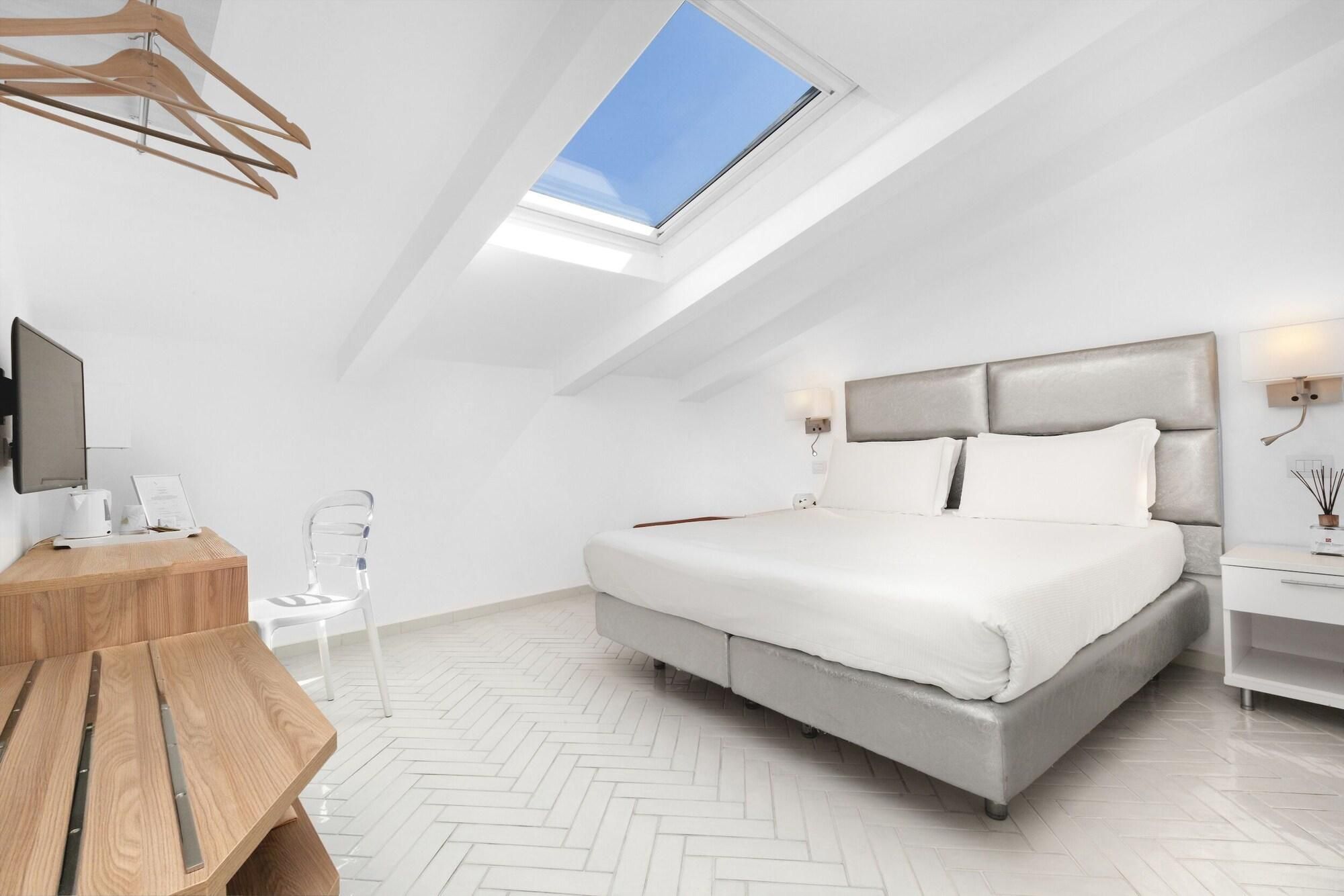 Un dormitorio moderno con tragaluces, una cama, una mesita de noche y un escritorio con una silla.