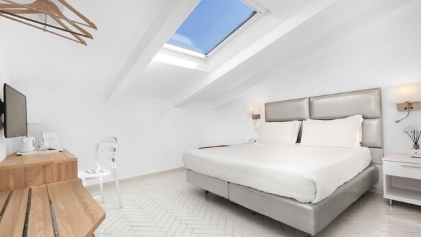 Ein modernes Schlafzimmer mit Oberlichter, einem Bett, einem Nachttisch und einem Schreibtisch mit Stuhl.