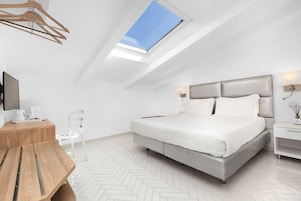 Un dormitorio moderno con tragaluces, una cama, una mesita de noche y un escritorio con una silla.