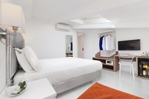 Une chambre d’hôtel moderne équipée d’un lit, d’un bureau, d’une chaise, d’une télévision et d’une salle de bain.