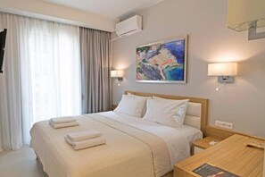 Une chambre d’hôtel avec un lit, des lampes de chevet, un tableau au mur et une fenêtre avec des rideaux.