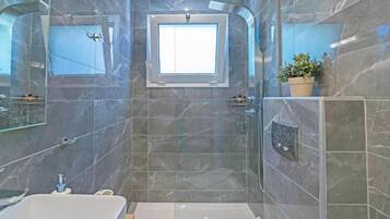 A modern bathroom with a bathtub, a shower, and a small window.