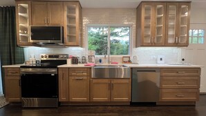 A modern kitchen with wooden cabinets, stainless steel appliances, and a large window providing natural light. - Elegant Escape by Downtown Burr Ridge with an easy access to Chicago Landmarks (La Grange)