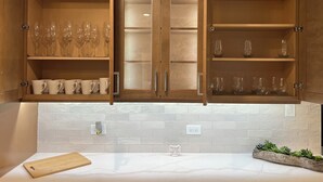 A kitchen with wooden cabinets, a marble countertop, and a cutting board. - Elegant Escape by Downtown Burr Ridge with an easy access to Chicago Landmarks (La Grange)