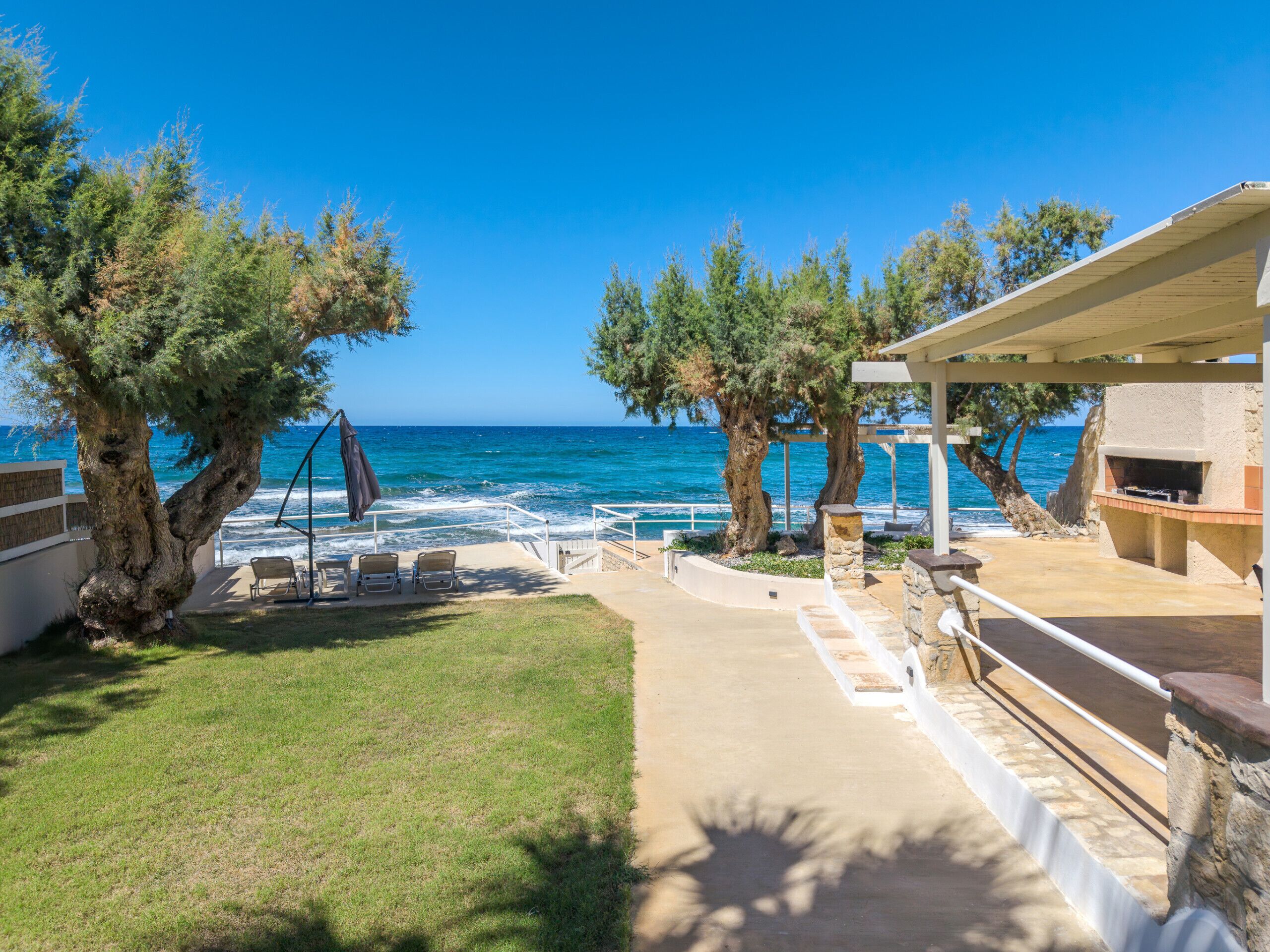 A coastal property with a patio, lounge chairs, and a view of the sea.