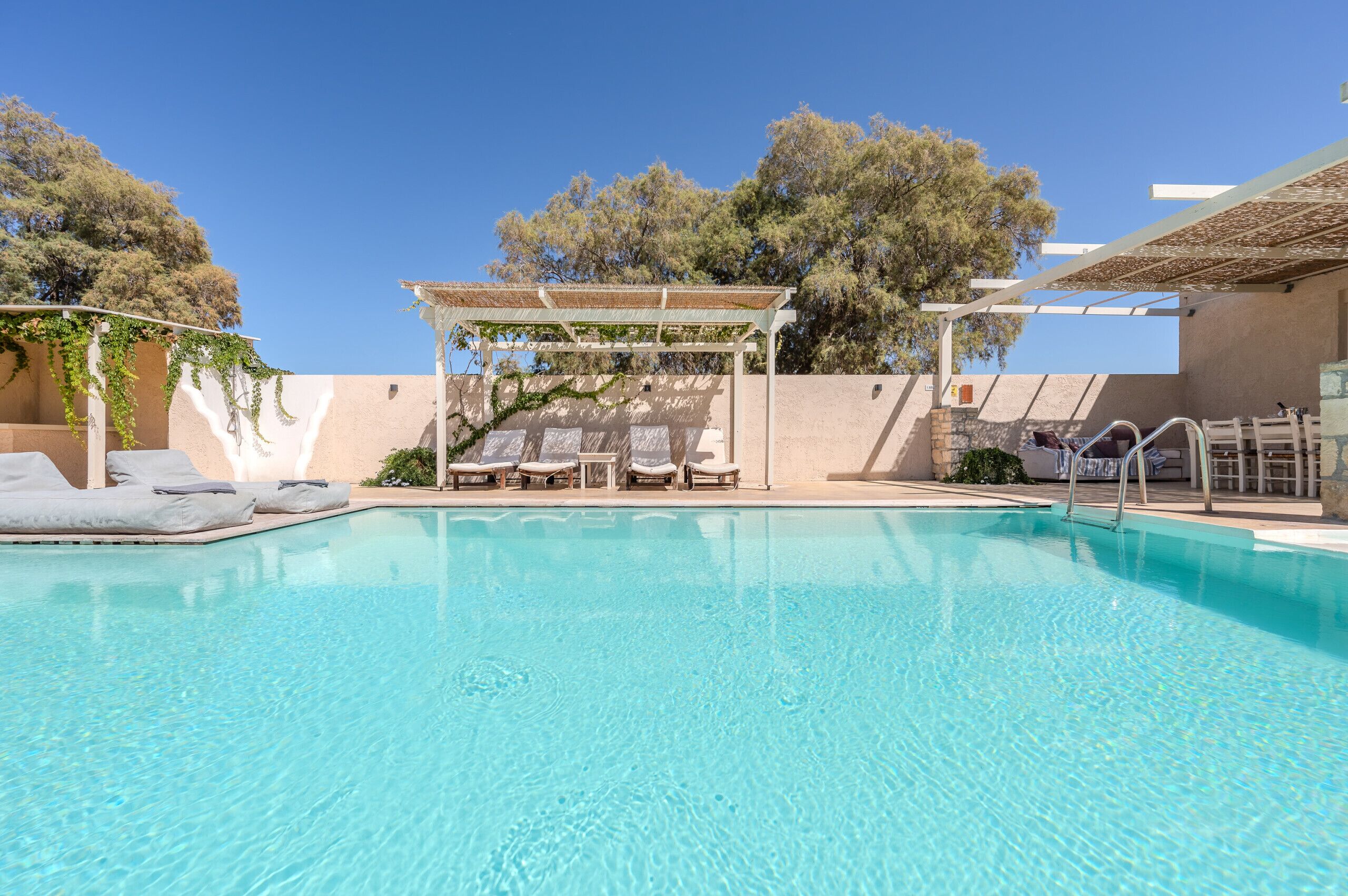A clear blue pool with lounge chairs and a pergola.