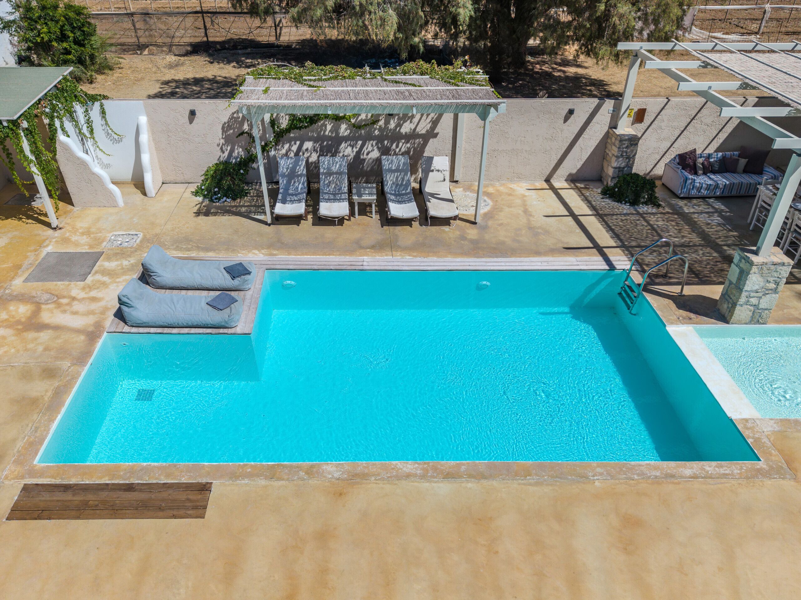 Una piscina rectangular amb una terrassa de fusta i seients per relaxar-se.