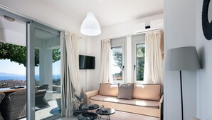 Een moderne woonkamer met een bank, een televisie en een eetgedeelte met stoelen en een tafel.
