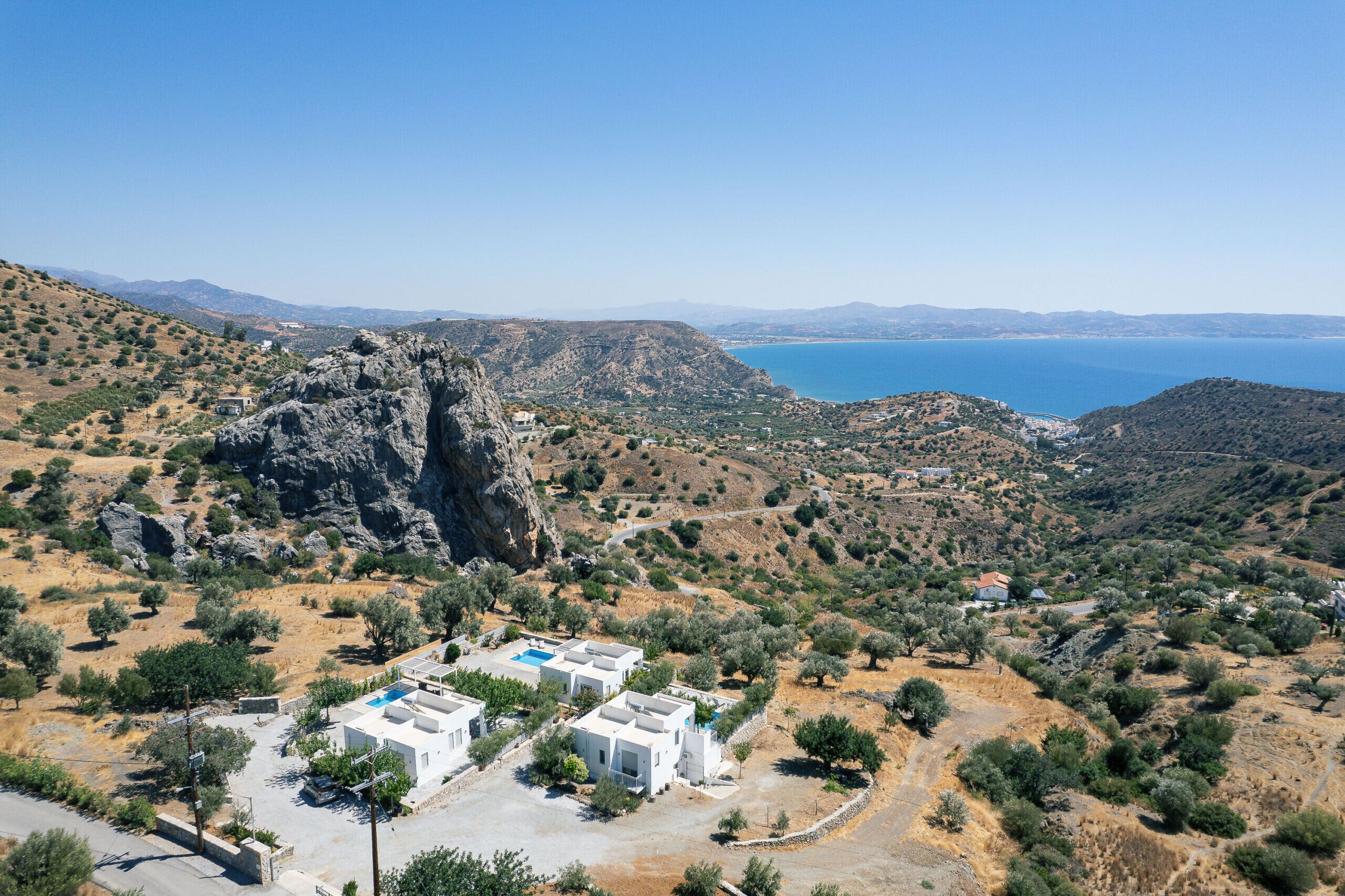 A coastal property with white buildings, a rocky cliff, and a view of the sea.