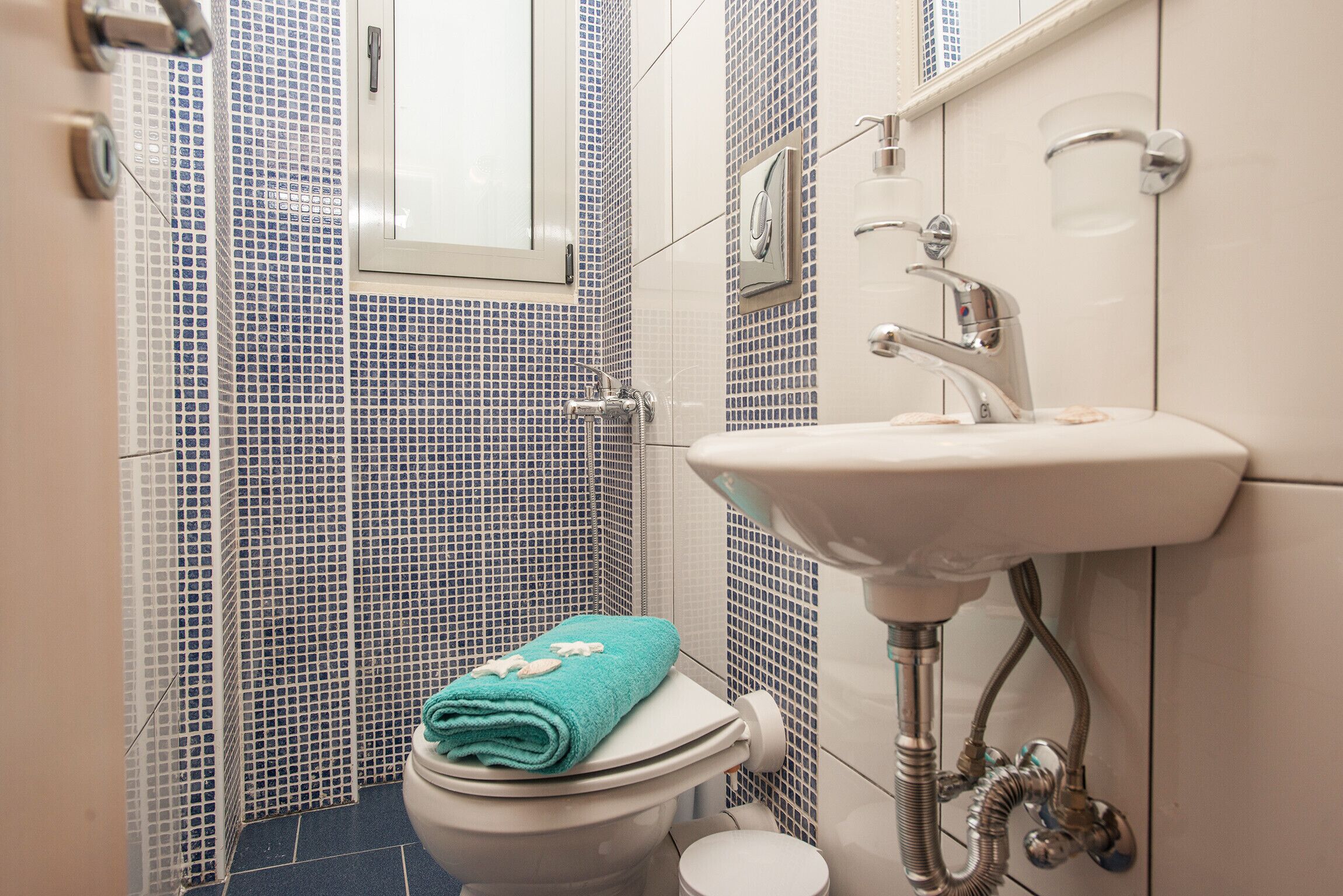 Une salle de bain avec des toilettes, un lavabo et des murs carrelés.