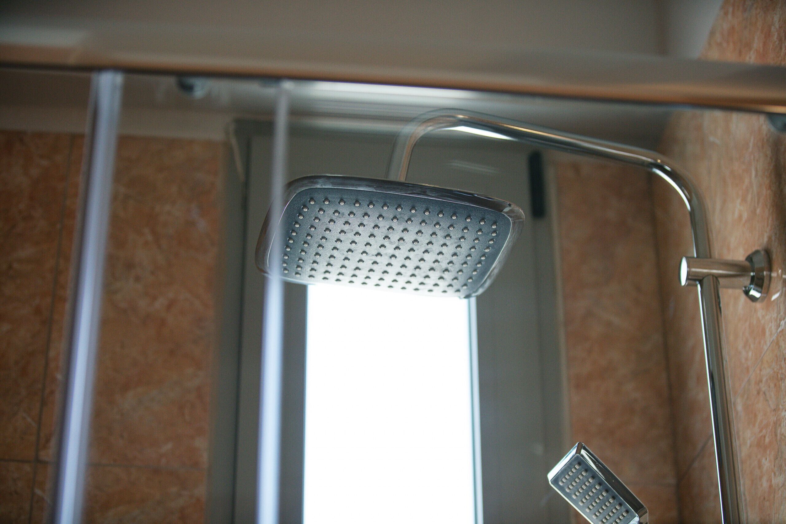 Une douche équipée d’un pommeau de douche à main et d’un pommeau de douche fixe.