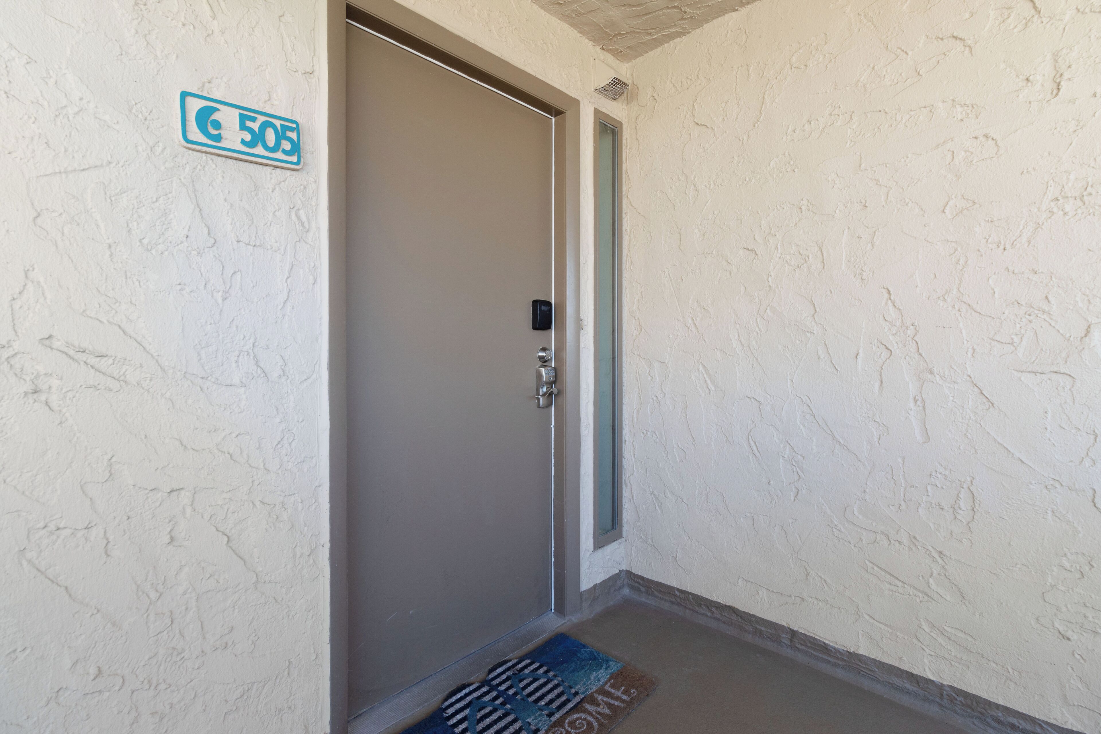 A door with a number sign, a doorbell, and a doormat.
