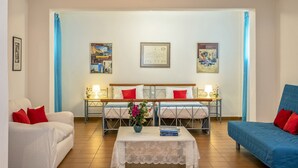Ein Hotelzimmer mit Bett, einer Couch, einem Couchtisch mit Vase und einem Schreibtisch mit Lampe.