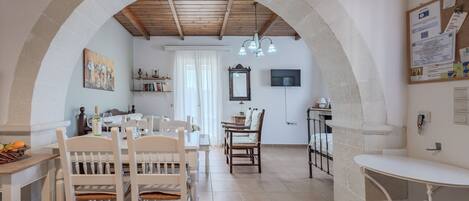 A spacious dining area with a high arched ceiling, a chandelier, and a view of the kitchen.