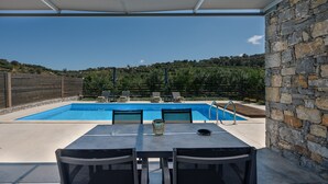 A covered outdoor area with a pool, stone wall, and seating. - Kalostous Villas (Rethymno)