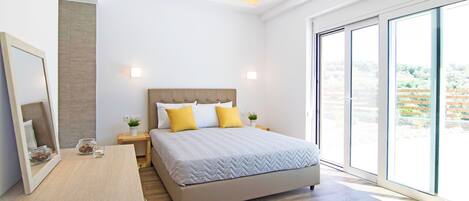 Une chambre moderne avec un grand lit, une table de chevet, un miroir et une vue dégagée grâce à de grandes fenêtres.