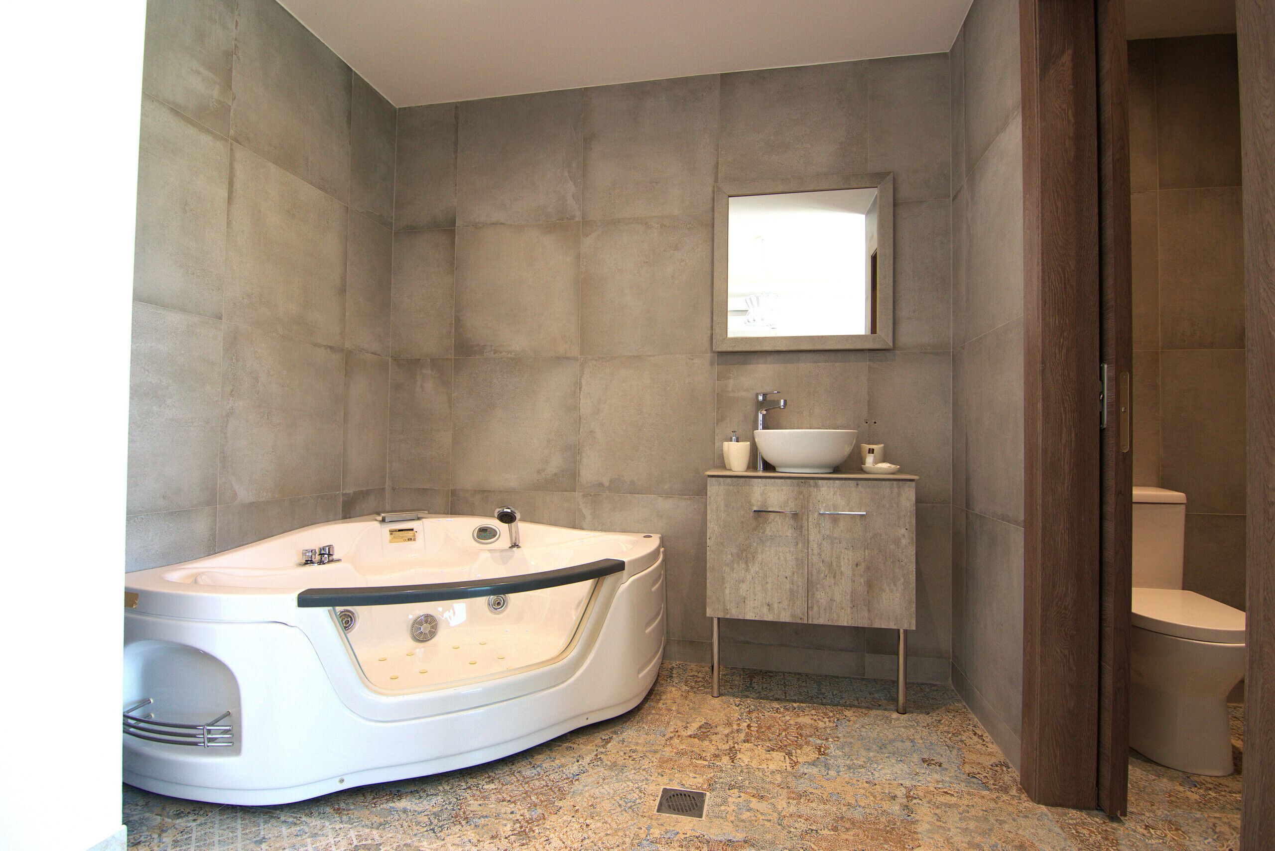 A modern bathroom with a freestanding bathtub, a sink with a mirror above it, and a toilet.