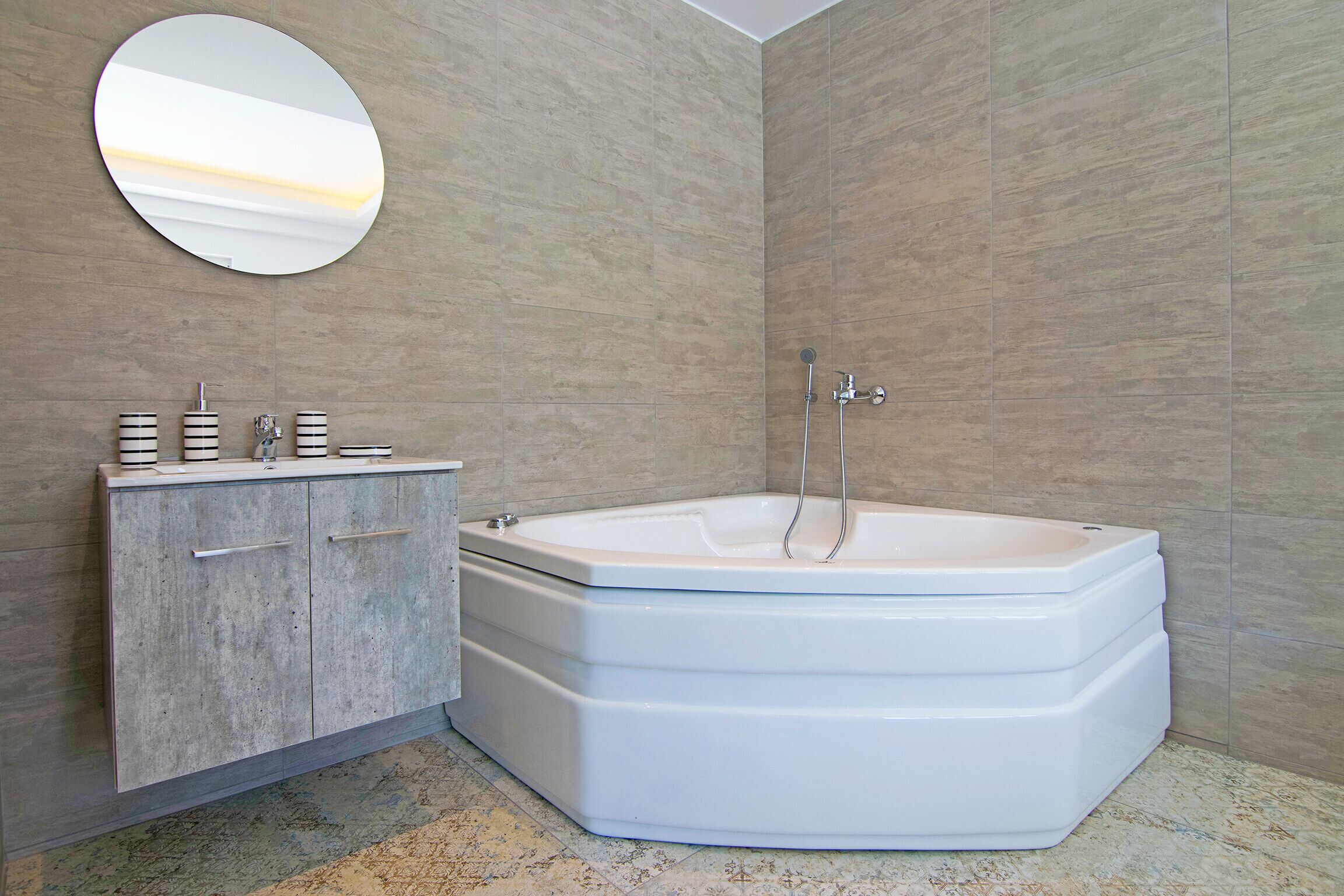 A modern bathroom with a freestanding bathtub, a vanity with a mirror, and a tiled floor.