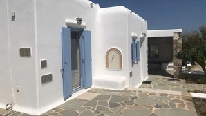A white building with blue doors and a stone-paved entrance. - Villa Verdi Mykonos (mykonos)