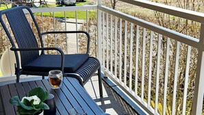 Un balcon avec deux chaises, une table, une plante en pot et une tasse de thé.
