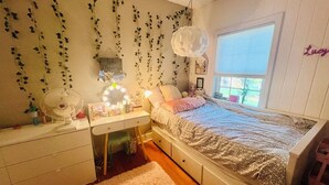 A bedroom with a bed, bedside table, dresser, and a window. - Beautiful home with large yard (Canton)