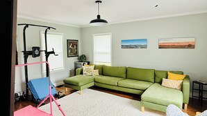 A living room with a green sofa, a white rug, a pink exercise bike, and a ceiling light. - Beautiful home with large yard (Canton)