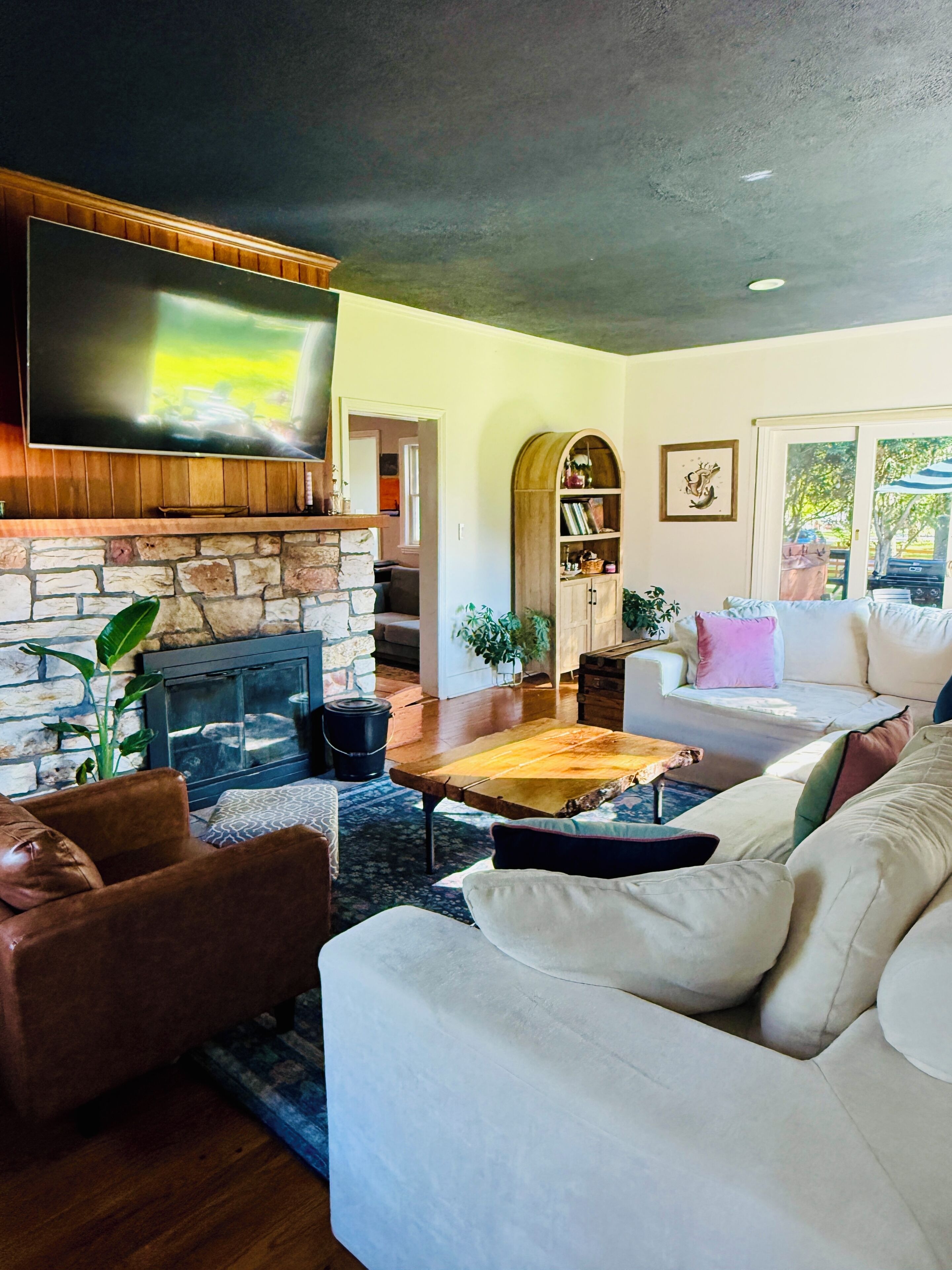 A living room with a stone fireplace, a flat-screen TV, a sofa, and a coffee table.