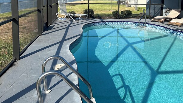 Piscina techada con vistas claras del entorno, que incluye un césped y una masa de agua.