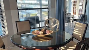 Un comedor con una mesa redonda de vidrio, cuatro sillas y un centro decorativo.