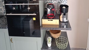 A compact kitchen with a microwave, coffee maker, and a small potted plant on a shelf.