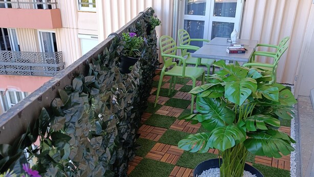 A balcony with a checkered floor, potted plants, and a table with chairs.