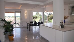 A modern kitchen with a dining area, large windows, and a potted plant. - The Beach House (Seignosse)