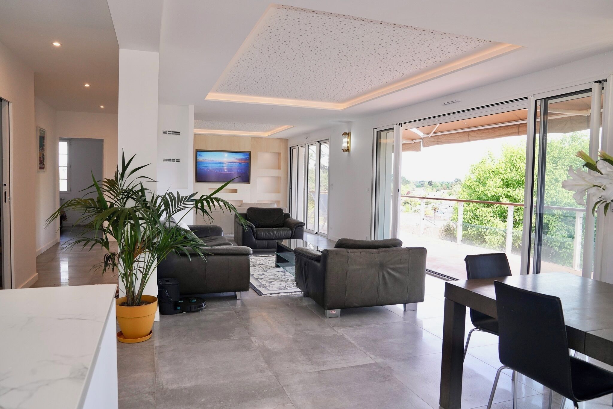 Un salon moderne avec un canapé, des fauteuils, une table basse et un téléviseur fixé au mur.
