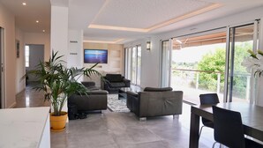 A modern living room with a sofa, chairs, a coffee table, and a TV mounted on the wall. - The Beach House (Seignosse)