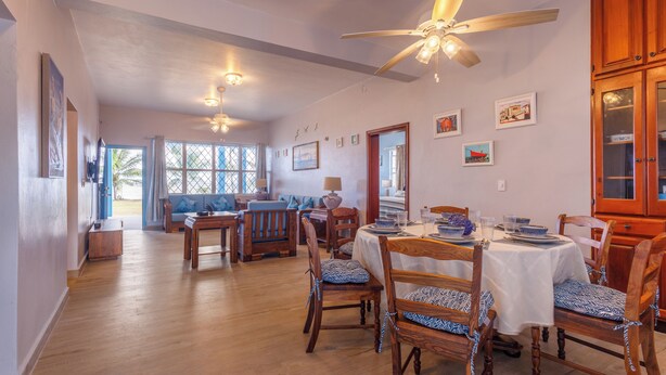 Un comedor con muebles de madera, ventilador de techo y vistas al exterior.