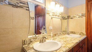 Un baño con dos lavamanos, un espejo grande y armarios de madera.